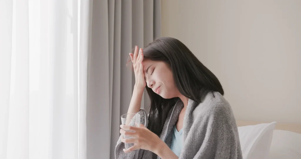 頭痛で薬を飲んでいる日本人女性の画像。